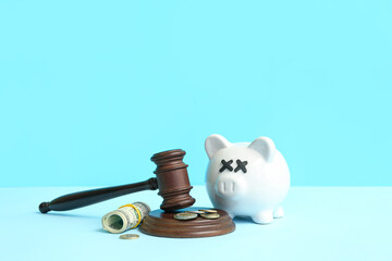 Piggy bank with judge gavel and money on blue background. Bankruptcy concept