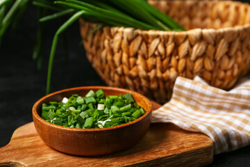 Bowl with fresh cut green onion on dark background