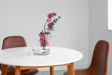 Beautiful ikebana on dining table in light room