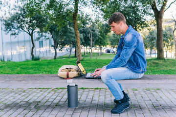 Obraz premium Profile of a young man working with a laptop outdoors