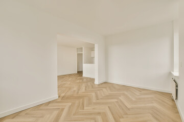 an empty room with parquet wood flooring and white walls in the corners on the right is a door