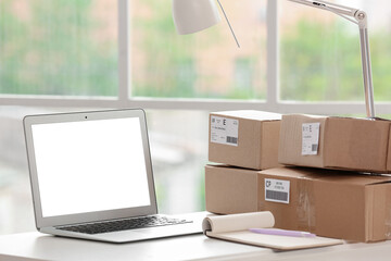 Workplace with laptop, notebook and parcels in office