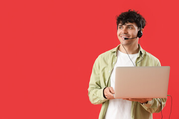 Male technical support agent with laptop on red background
