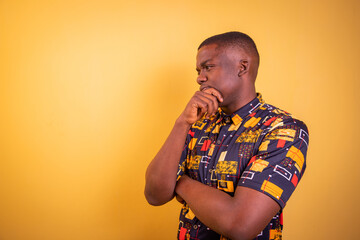 Thoughtful African man with hand on chin, studio photo with copy space