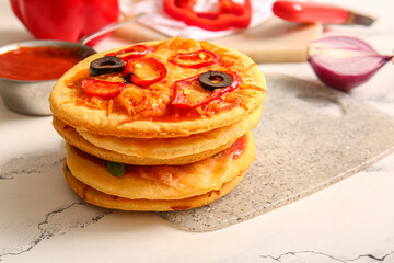 Board with different tasty mini pizzas on white table