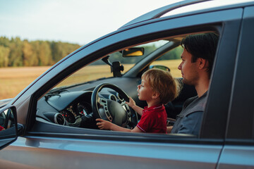 Father with his two year old son driving car in a field - 613642572