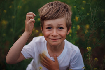 Portrait of delighted boy in a flower meadow