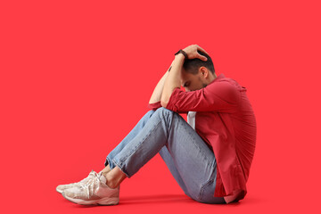 Young man having panic attack on red background