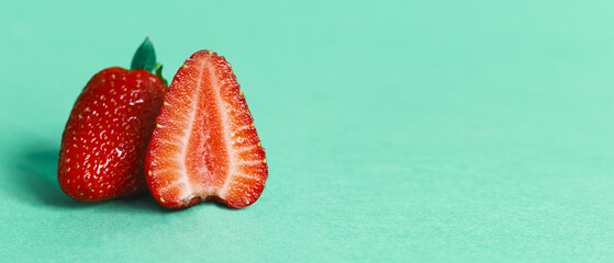 Two strawberries on a cyan background. Panorama for design with space for text. Header for design....