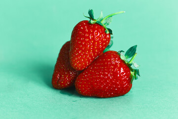 three strawberries on a cyan background
