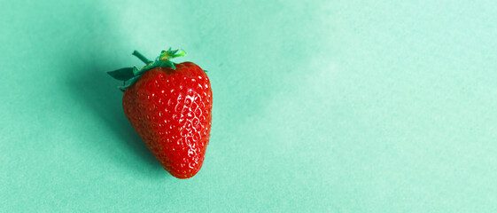 One strawberry on a cyan background. Panorama for design with place for text. Header for design....