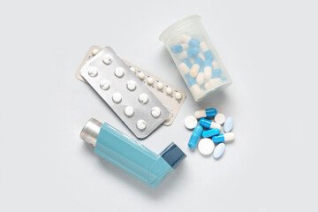 Asthma inhaler and box with pills on grey background
