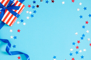 Obraz premium 4th of July, USA Presidents Day, Independence Day. Flat lay top view of patriotic wrapping paper and gift box twinkling confetti on blue background with space, promotion or greeting message, banner