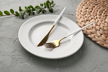 Plate with golden fork, knife and cotoneaster twig on green grunge background
