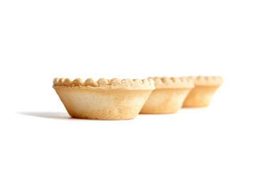 Three empty tartlet shells isolated on white background. Crispy mini tart shells closeup