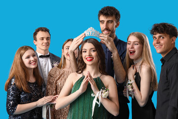 Young people crowning prom queen on blue background © Pixel-Shot