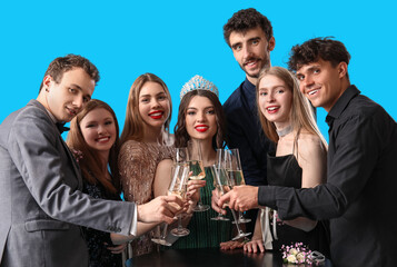 Young people dressed for prom drinking champagne on blue background