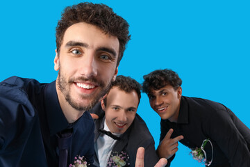 Young men dressed for prom taking selfie on blue background, closeup © Pixel-Shot
