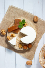 Top view of a still life of fresh goat cheese, quince jelly and walnuts.