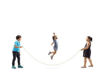 Full length profile shot of a boy and two girls playing skipping rope - obrazy, fototapety, plakaty