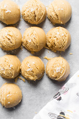 Scoops of vanilla cookie dough on a parchment lined cookie sheet, plain vanilla cookie dough about to be baked