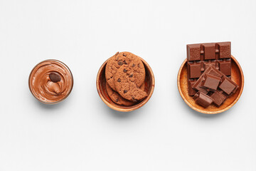 Bowls with cookies, chocolate and cream on white background
