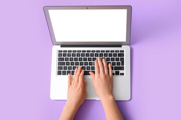 Female hands with modern laptop on purple background