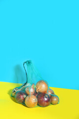 Eco bag with different kinds of onion on color background