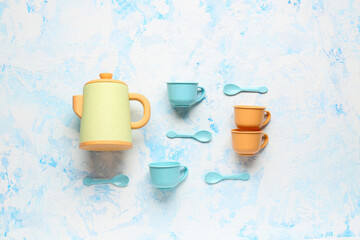 Teapot with cups and spoons for baby on grunge blue background