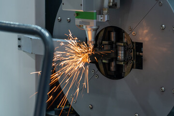 Automatic machine cuts a stainless square pipe with a laser with sparks flying in all directions