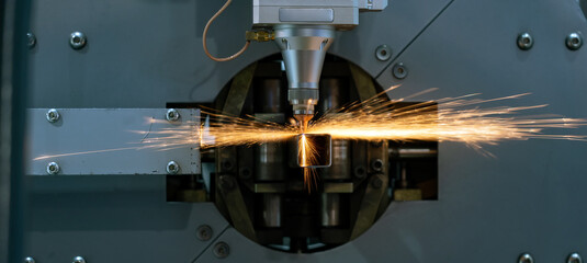 Automatic machine cuts a stainless square pipe with a laser with sparks flying in all directions