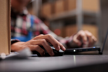 Postal warehouse employee checking delivery customer satisfaction on laptop. Post office storehouse...