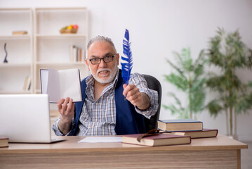 Old male writer sitting at workplace