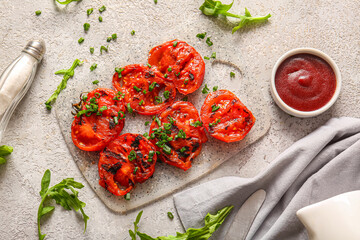 Board with tasty grilled tomatoes and green onion on grey background
