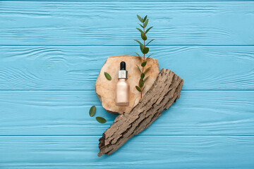 Composition with bottle of cosmetic product, stone, tree bark and eucalyptus branch on color wooden background