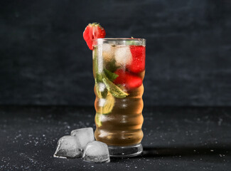 Glass of ice tea with strawberry and mint on black background
