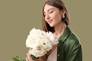 Naklejka premium Beautiful young woman with bouquet of peony flowers on green background