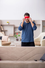 Blindfolded young man at home