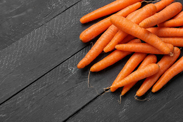 Many fresh carrots on black wooden background
