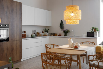 Interior of modern kitchen with glowing lamp and teapot on dining table