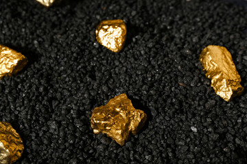 Golden nuggets on black coal, closeup
