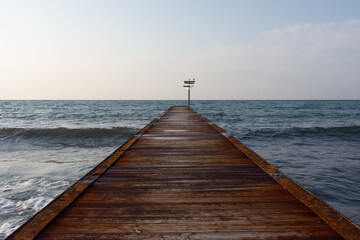 pontile sul mare con cartello e gabbiani