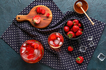 Glass and jug of infused water with strawberry on black background