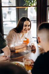 Young smiling woman enjoying a coctail in bar restaurant during rest with friends.  Celebration and party concept