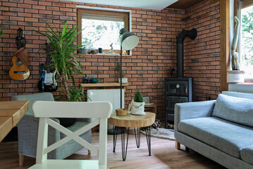 Stylsih design in interior of room in rural cottage with fireplace, red brick wall, wooden...