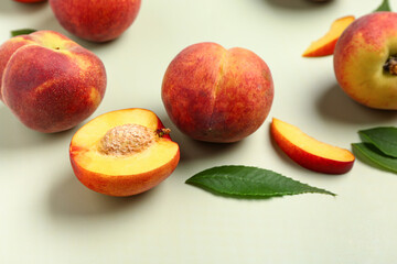 Sweet peaches and leaves on light background