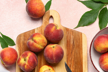 Board and bowl with sweet peaches on pink background