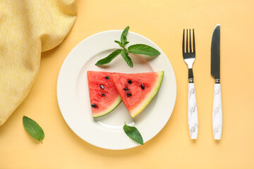 Plate with pieces of fresh watermelon and mint on yellow background