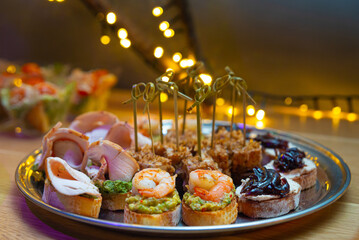 Set of bruschetta and canapes on a plate. Tapas with guacamole and prawn, tapas with caramelized onions, bruschetta with turkey fillet. Tuna canapes with tuna shavings.