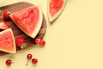 Board with pieces of fresh watermelon and different berries on yellow background